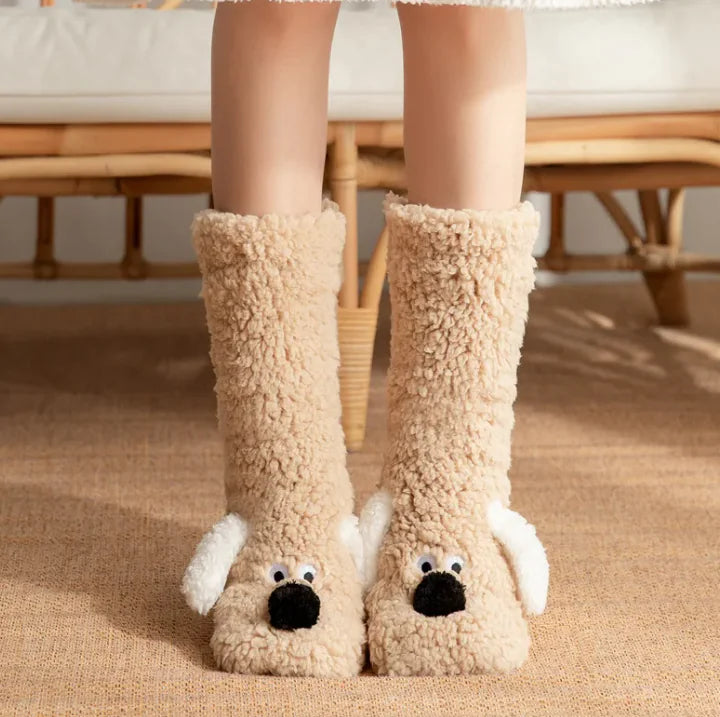 Beige fuzzy dog-shaped slippers worn by a person indoors.