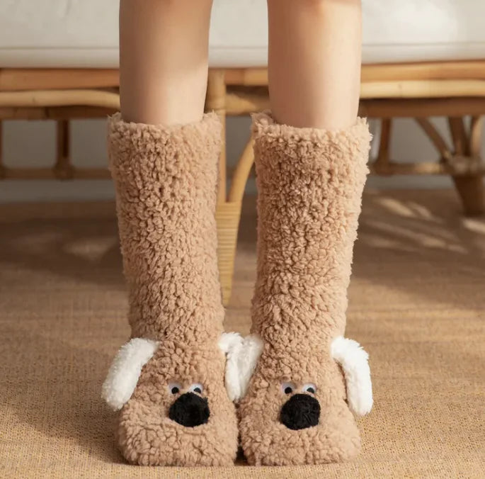 Brown dog-themed slippers worn by a person on a carpeted floor.