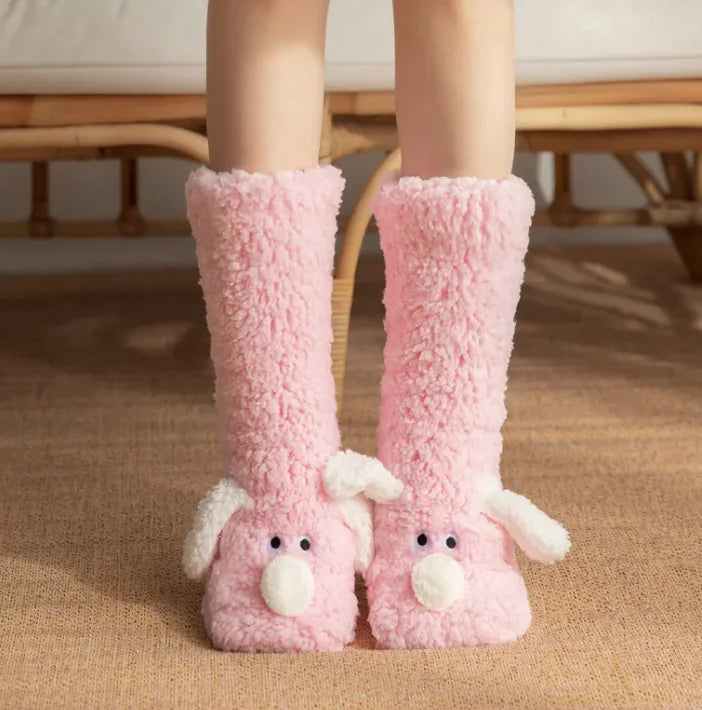 Pink fuzzy slippers with animal faces on a carpeted floor.