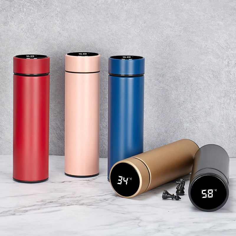Set of colorful thermos bottles with digital temperature displays on a marble surface.